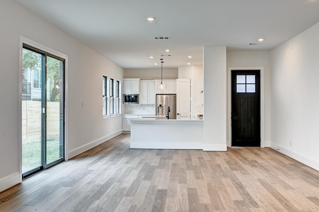 kitchen with white cabinets, visible vents, stainless steel appliances, light countertops, and light wood finished floors