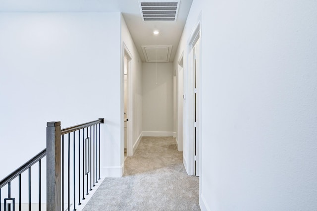 hall featuring attic access, an upstairs landing, visible vents, carpet, and baseboards