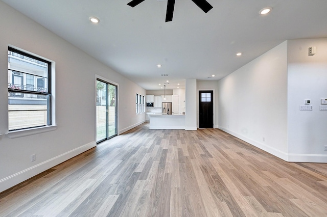 unfurnished living room with baseboards, recessed lighting, ceiling fan, and light wood-style flooring