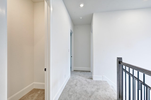 hallway with an upstairs landing, baseboards, and carpet floors