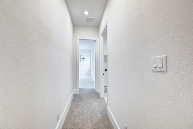 hall featuring baseboards, visible vents, and carpet floors