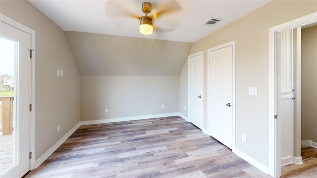 bonus room with light wood-style floors, a ceiling fan, visible vents, baseboards, and lofted ceiling