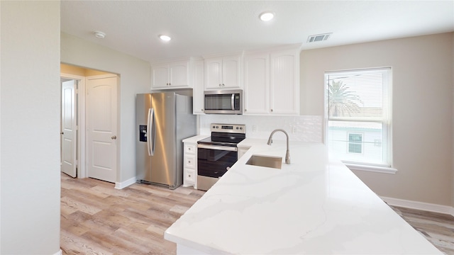 511 Caisson St, Surfside Beach, TX 77541 - kitchen with appliances with stainless steel finishes, a sink, light stone countertops, white cabinets, and light wood finished floors