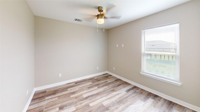 empty room with baseboards, visible vents, ceiling fan, and light wood finished floors