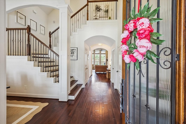 entryway featuring stairway, arched walkways, a high ceiling, and wood-type flooring