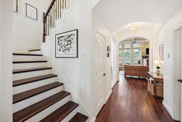 entrance foyer with baseboards, ceiling fan, dark wood-style floors, stairway, and arched walkways