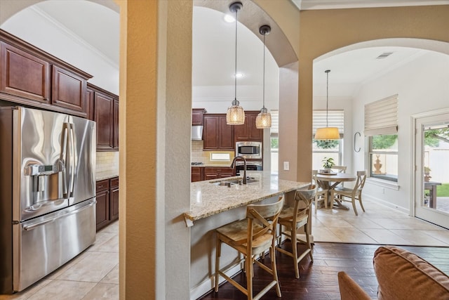 kitchen featuring crown molding, light stone counters, a sink, backsplash, and stainless steel appliances