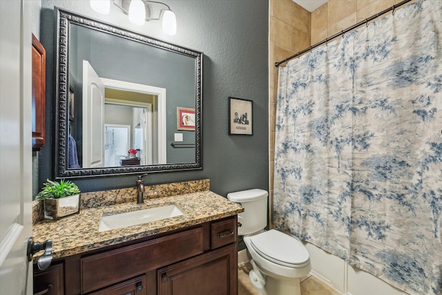 bathroom with vanity, a textured wall, toilet, and shower / tub combo