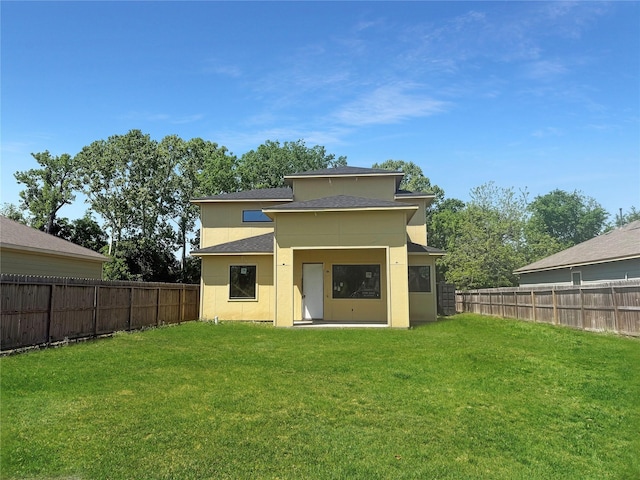 rear view of property featuring a fenced backyard, a shingled roof, and a yard
