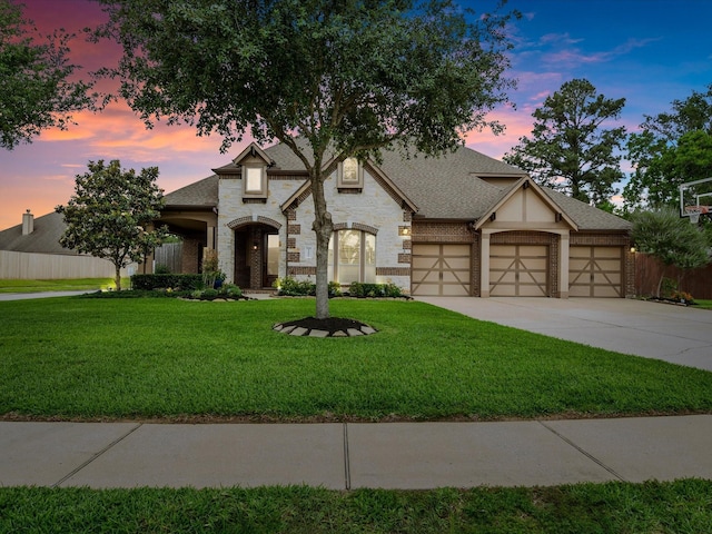 french provincial home featuring a front lawn, fence, driveway, and stone siding