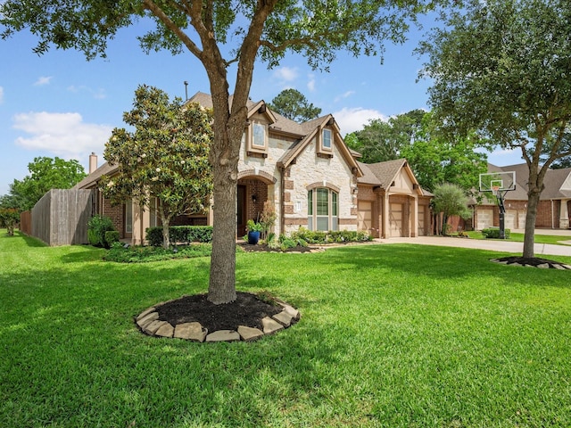 view of front of home featuring driveway, fence, a front yard, and stone siding