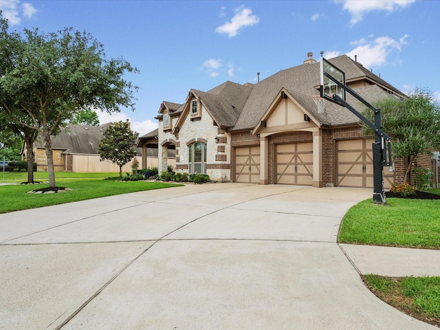 french country inspired facade featuring a front lawn, stone siding, brick siding, an attached garage, and driveway