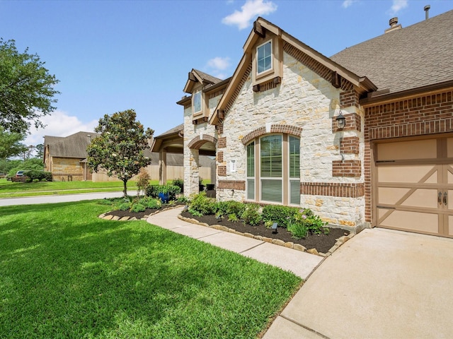 view of front of property featuring an attached garage, a shingled roof, a front lawn, stone siding, and concrete driveway