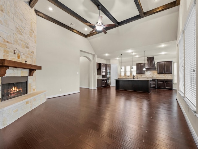 unfurnished living room featuring visible vents, a sink, a fireplace, lofted ceiling with beams, and a ceiling fan