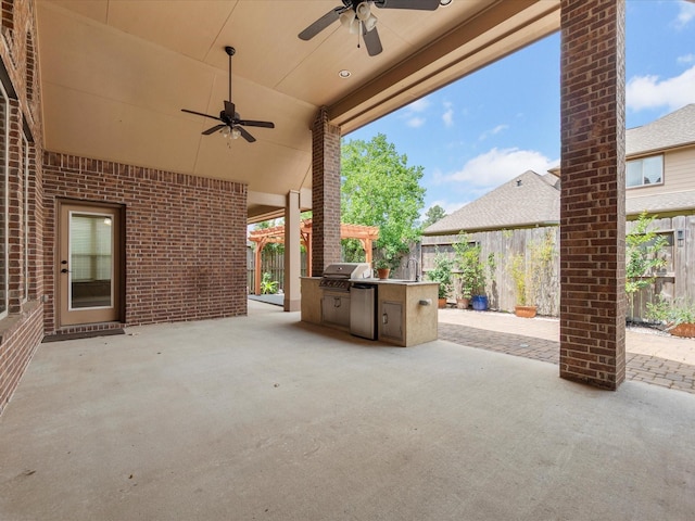 view of patio featuring grilling area, ceiling fan, a sink, fence, and an outdoor kitchen