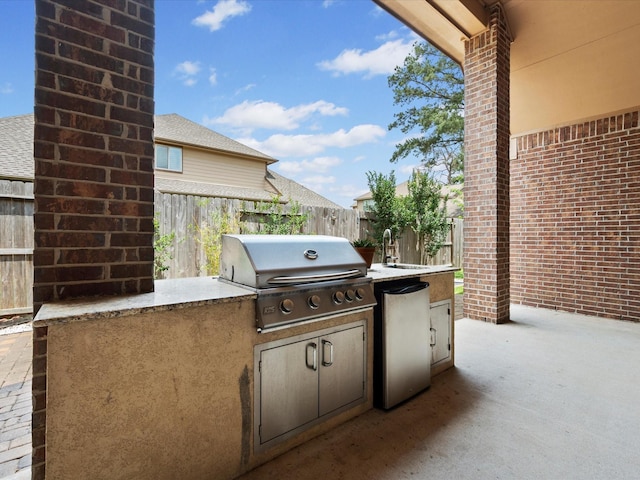 view of patio featuring an outdoor kitchen, fence, a sink, and area for grilling