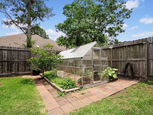 view of yard featuring a greenhouse, an outdoor structure, and a fenced backyard