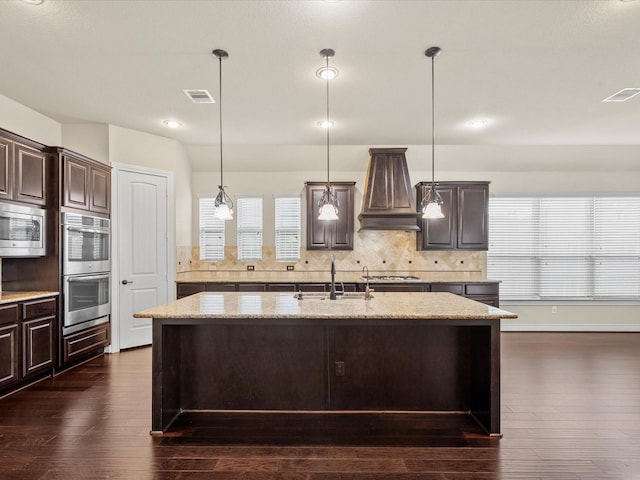 kitchen with stainless steel appliances, dark brown cabinetry, visible vents, and custom exhaust hood
