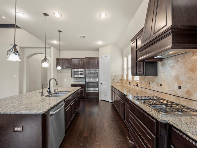 kitchen featuring visible vents, custom exhaust hood, dark brown cabinets, a sink, and appliances with stainless steel finishes