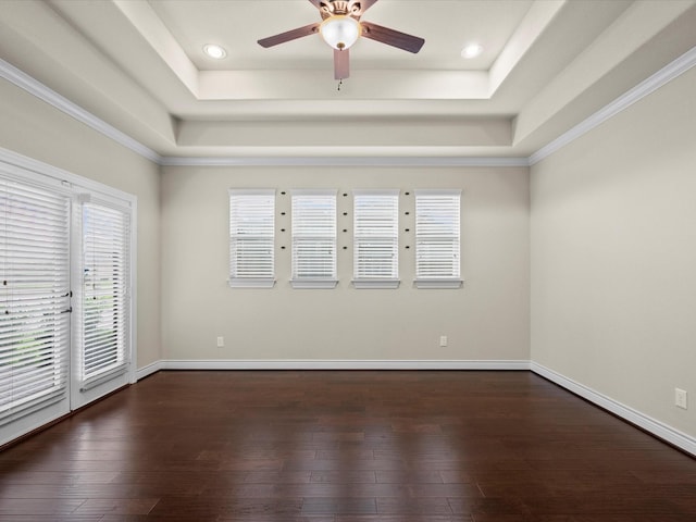 empty room featuring ceiling fan, ornamental molding, a tray ceiling, and dark wood-style flooring
