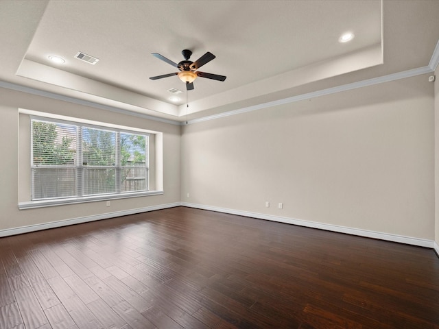 empty room with ceiling fan, a raised ceiling, baseboards, visible vents, and dark wood-style floors