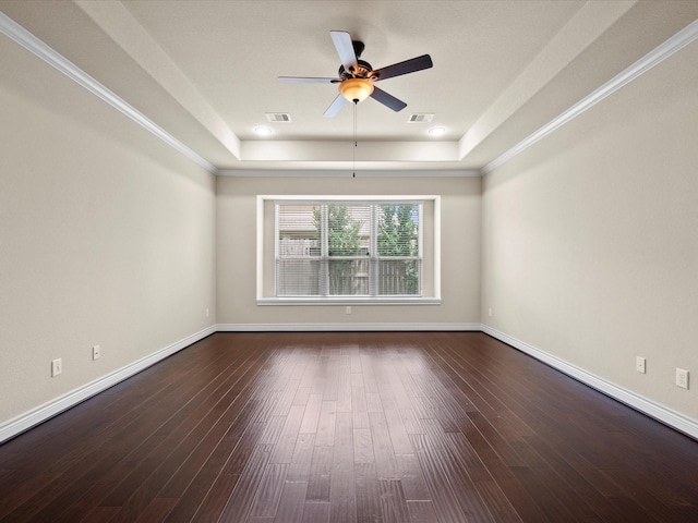 empty room featuring dark wood-style flooring, a raised ceiling, a ceiling fan, baseboards, and visible vents