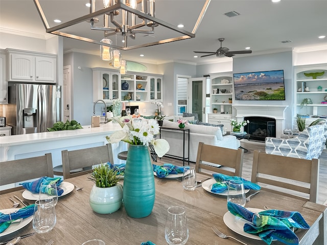 interior space featuring a glass covered fireplace, visible vents, crown molding, and recessed lighting
