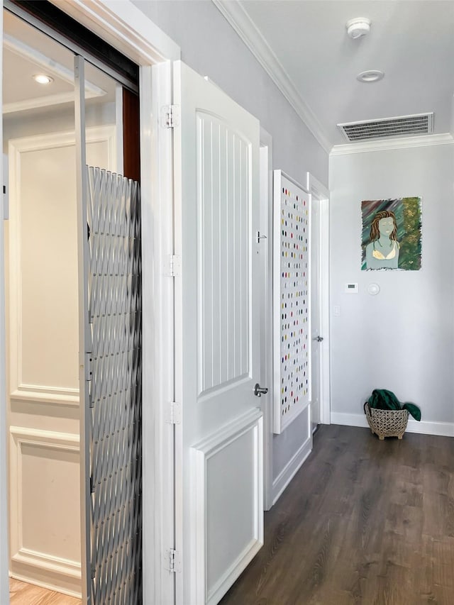 hall featuring visible vents, ornamental molding, dark wood-style floors, and baseboards