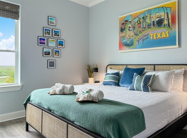 bedroom featuring crown molding, wood finished floors, and baseboards