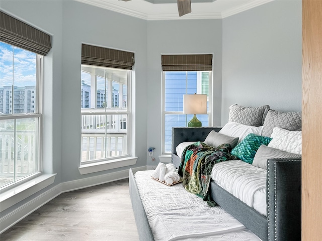 bedroom with baseboards, wood finished floors, multiple windows, and crown molding