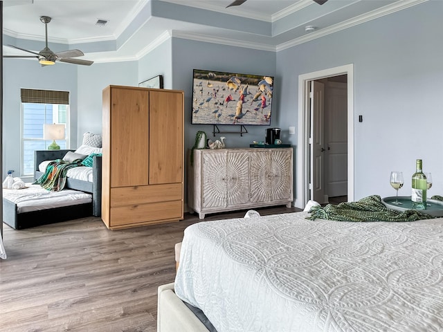 bedroom with ornamental molding, wood finished floors, ceiling fan, and visible vents