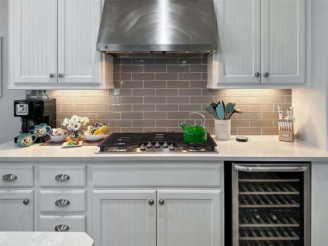 kitchen featuring wall chimney range hood, beverage cooler, light countertops, and white cabinets