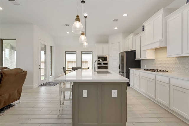 kitchen with visible vents, stainless steel appliances, decorative backsplash, and a sink