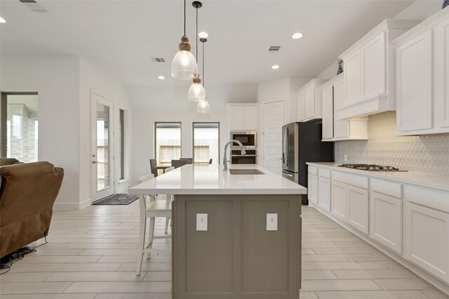 20514 Yearling Pasture Ln, Tomball, TX 77377 - kitchen featuring backsplash, stainless steel appliances, an island with sink, light countertops, and white cabinets