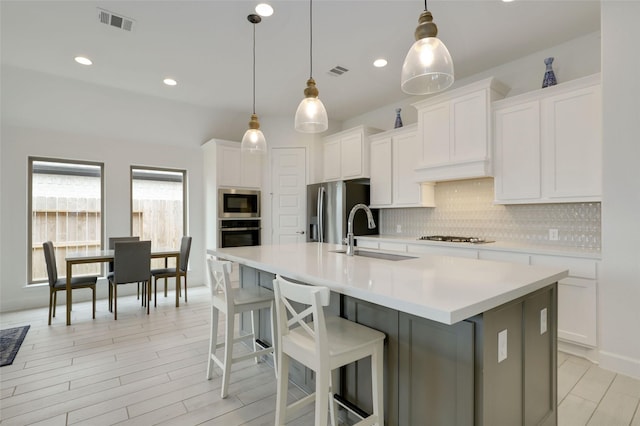 kitchen featuring appliances with stainless steel finishes, light countertops, decorative backsplash, and a sink