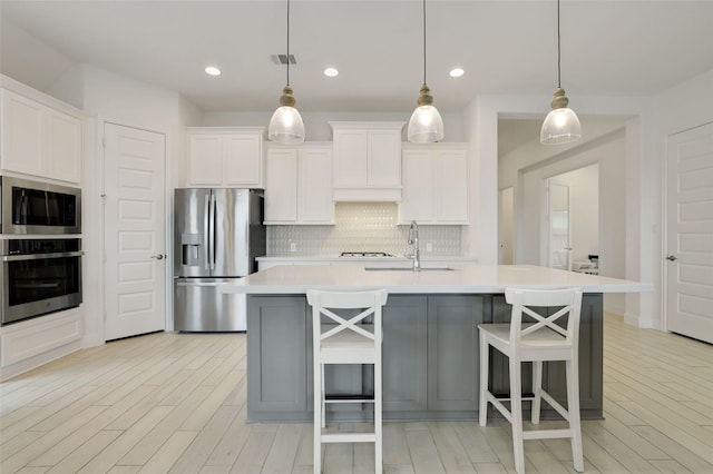 20514 Yearling Pasture Ln, Tomball, TX 77377 - kitchen with stainless steel appliances, decorative backsplash, light countertops, light wood finished floors, and white cabinets