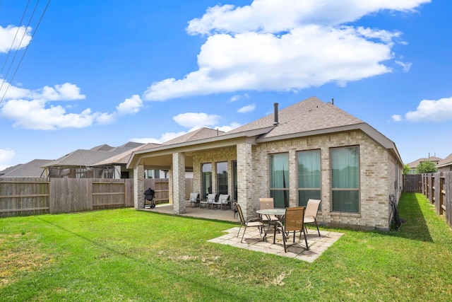 back of house featuring a patio, a shingled roof, a fenced backyard, a lawn, and brick siding