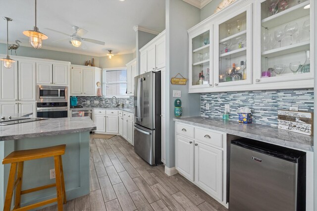 19427 Shores Dr, Galveston, TX 77554 - kitchen with a sink, decorative backsplash, white cabinetry, ornamental molding, and appliances with stainless steel finishes