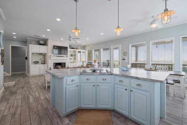 19427 Shores Dr, Galveston, TX 77554 - kitchen with crown molding, ceiling fan, a kitchen island, dark wood-style flooring, and a fireplace