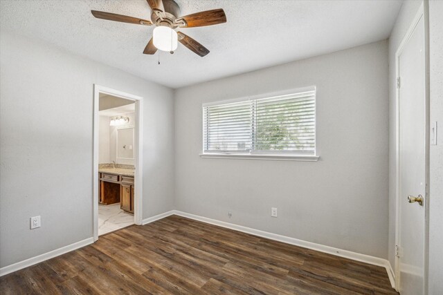 3206 Crossfell Rd, Spring, TX 77388 - unfurnished bedroom featuring dark wood-style floors, baseboards, ensuite bath, a ceiling fan, and a textured ceiling