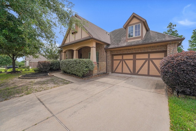 46 Chestnut Meadow Dr, Conroe, TX 77384 - english style home with driveway, a garage, brick siding, roof with shingles, and stucco siding