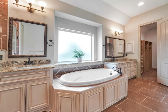 bathroom featuring lofted ceiling, two vanities, a sink, and a garden tub