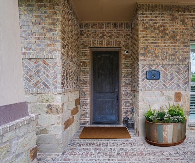 view of exterior entry with stone siding and brick siding