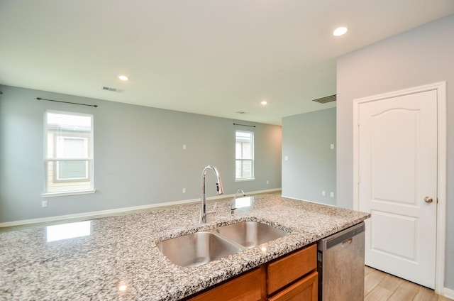 kitchen with light stone countertops, stainless steel dishwasher, brown cabinets, a sink, and visible vents