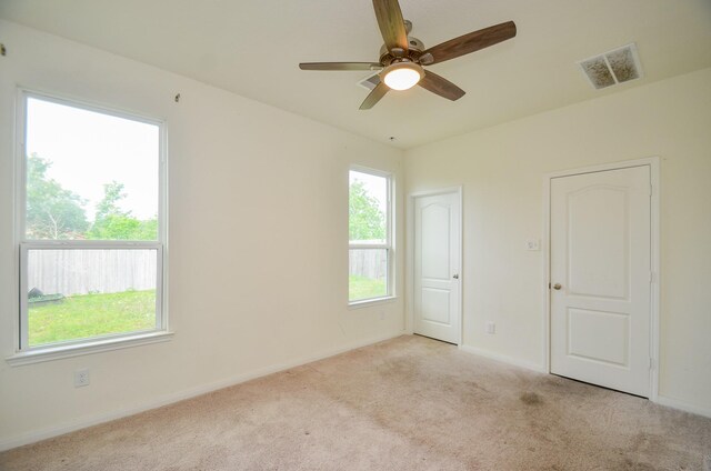 empty room with baseboards, visible vents, ceiling fan, and carpet flooring