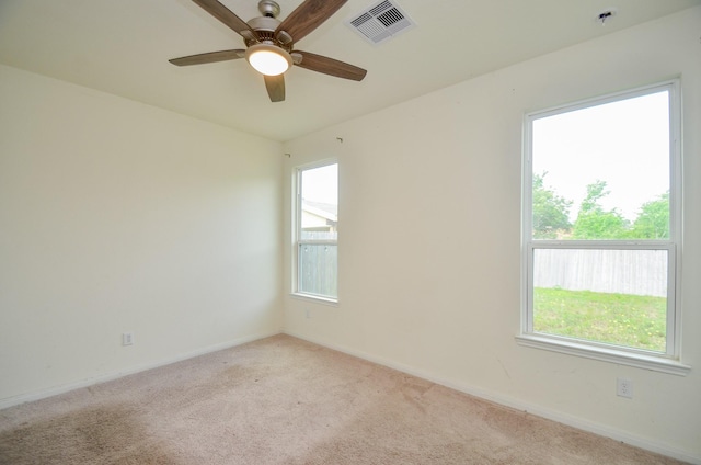 spare room with visible vents, ceiling fan, light colored carpet, and a healthy amount of sunlight