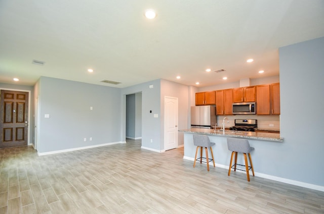 kitchen featuring light wood-type flooring, stainless steel appliances, recessed lighting, and baseboards