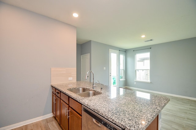 kitchen featuring a sink, light wood-style floors, visible vents, a peninsula, and stainless steel dishwasher