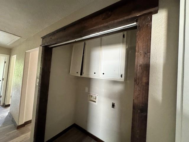 laundry room featuring hookup for an electric dryer, cabinet space, hookup for a washing machine, baseboards, and wood finished floors