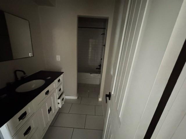 full bathroom with vanity, shower / bathtub combination, tile patterned floors, and baseboards